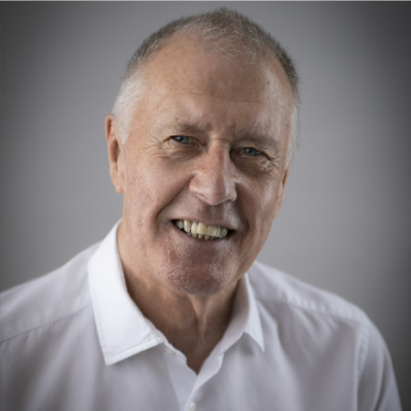 An image of Sir Geoff Hurst, wearing a white button-down shirt and smiling at the camera. 